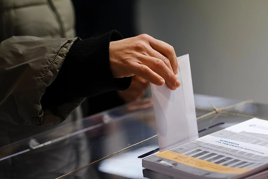 Ein Stimmzettel wird in eine Wahlurne geworfen.