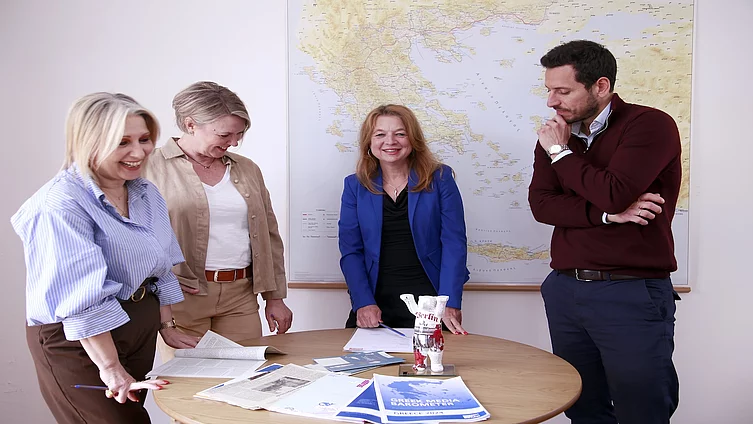 Das Team der FES Athen steht um einen Tisch herum und bespricht Publikationen.