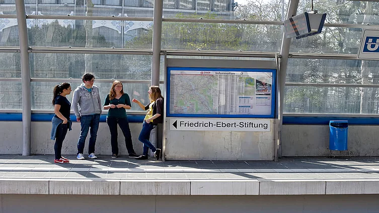 Junge Studierende unterhalten sich an einem Bahnsteig in Berlin.